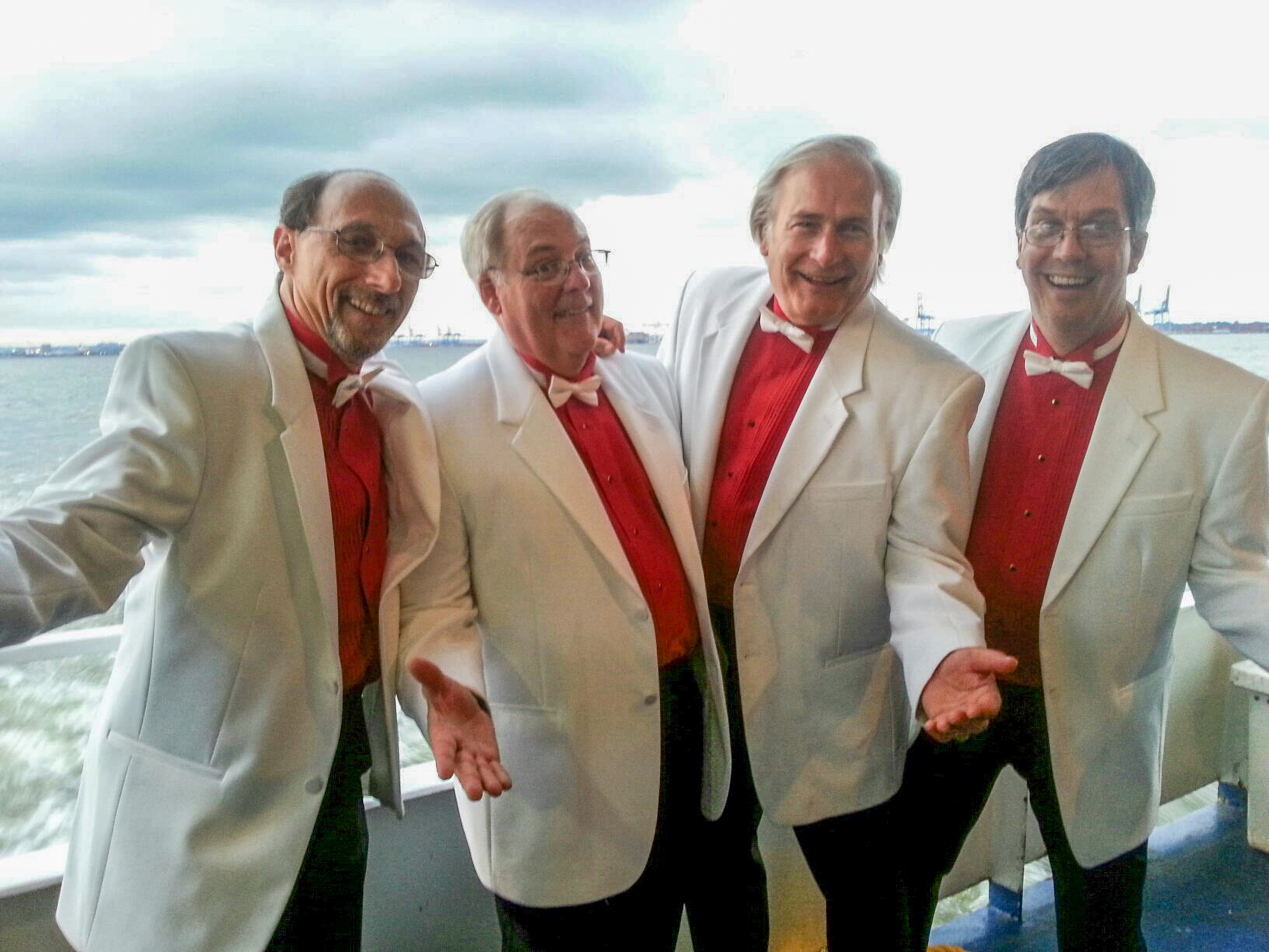 Image featuring 4 men in tuxedos singing.